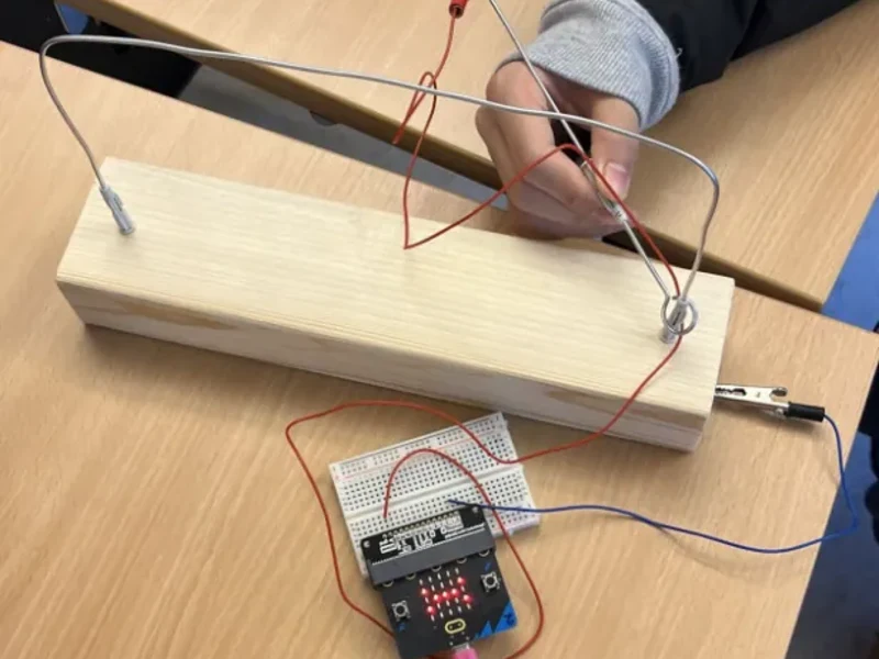 A wire game made in class: a bent wire on a wooden block, a loop, crocodile clips to a Micro:bit