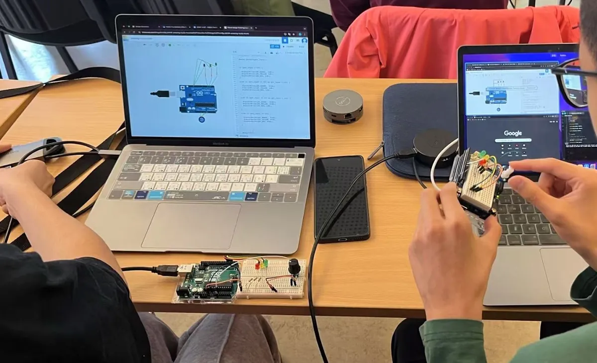 Students working with an Arduino and laptops