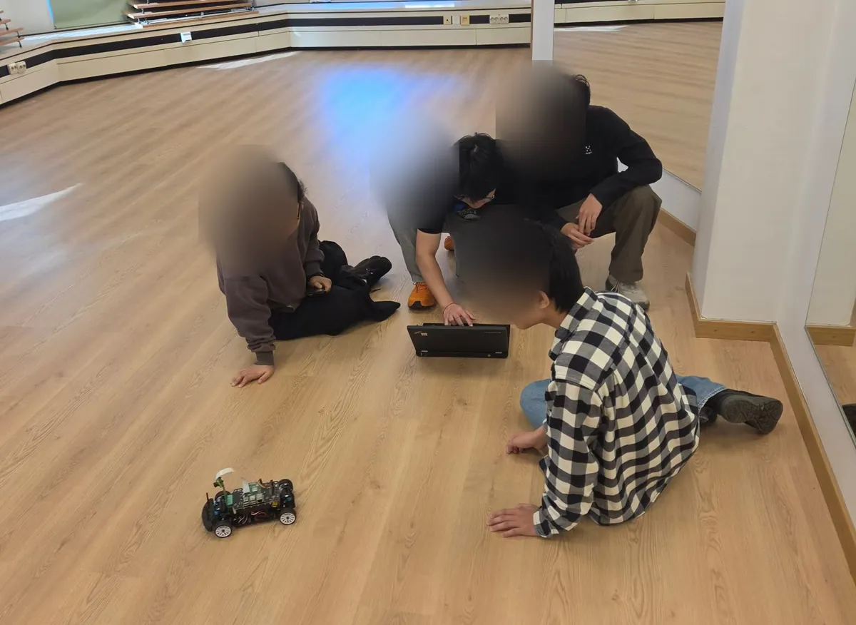 Students sitting on the floor watching their car drive