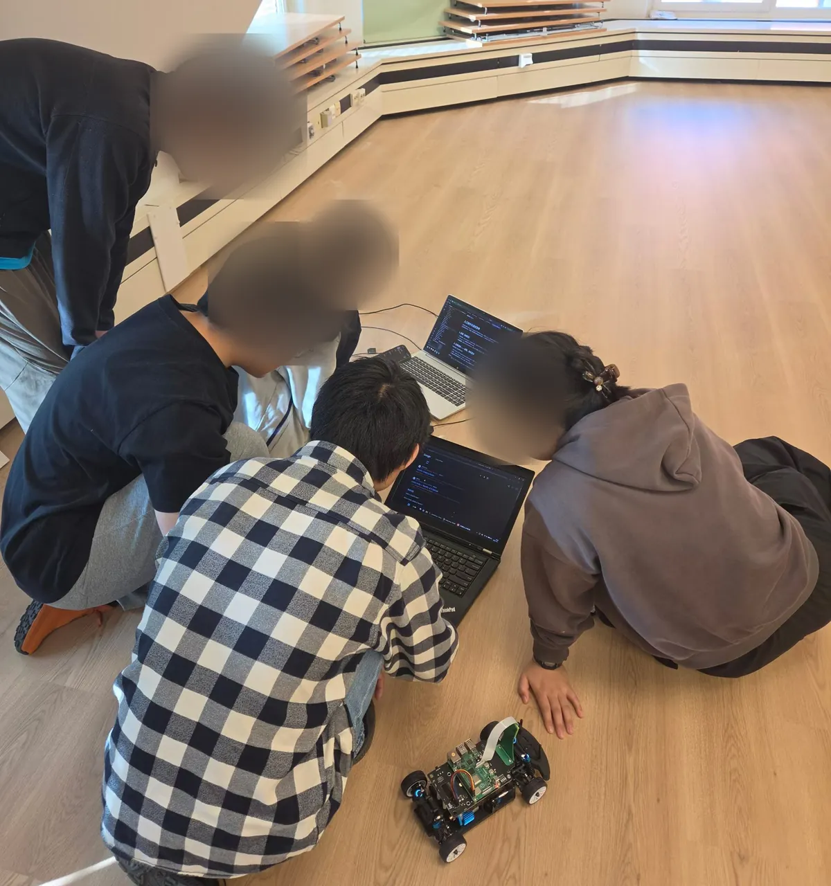 Students testing a robot car together on the floor
