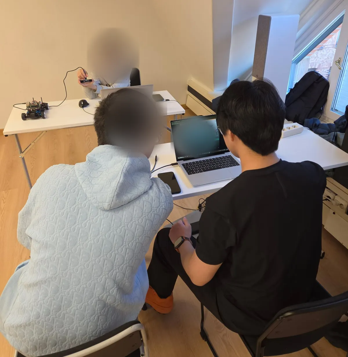 Two students working side by side at a laptop