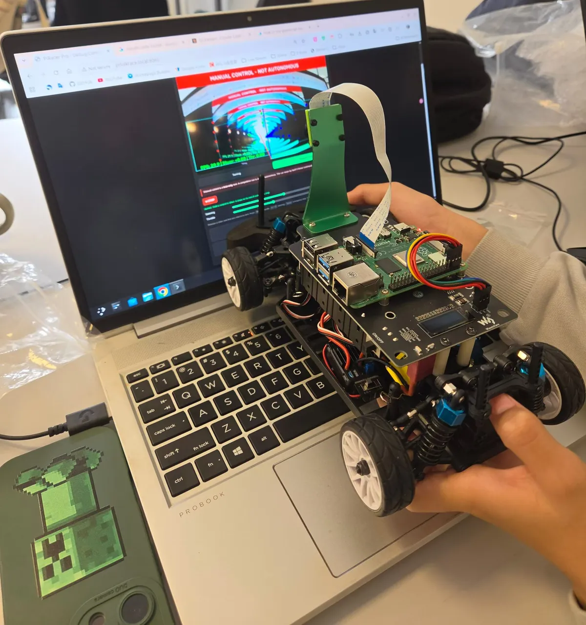 A student holds the car next to a laptop showing the camera image