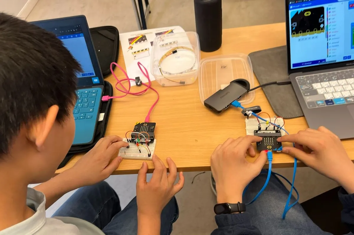 Two students testing their Micro:bit circuits side by side